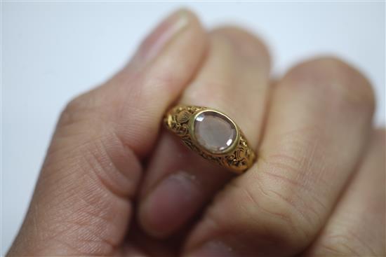 An antique scroll-pierced yellow metal ring set with an oval diamond,